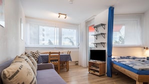 A cozy room with a sofa, a small table, a TV, and a bed. - Apartment “Förster” with Balcony and Wi-Fi (Überlingen)