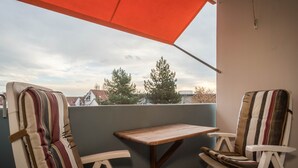 A balcony with two striped chairs, a wooden table, and a red umbrella. - Apartment “Förster” with Balcony and Wi-Fi (Überlingen)