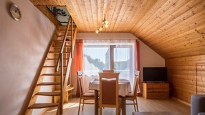 A wooden interior with a dining table, chairs, a TV, and a wooden staircase. - Holiday Apartment "Monika Haug" with Lake View, Mountain View, Wi-Fi, Balcony & Garden (Immenstaad am Bodensee)