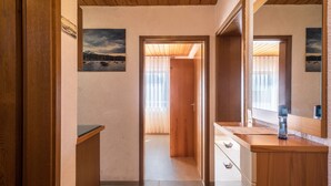 A hallway with wooden flooring, a wooden door, a mirror, and a small counter with a faucet. - Holiday Apartment "Monika Haug" with Lake View, Mountain View, Wi-Fi, Balcony & Garden (Immenstaad am Bodensee)