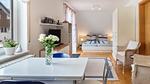 A compact living space with a dining area, a bed with striped bedding, and a kitchenette.