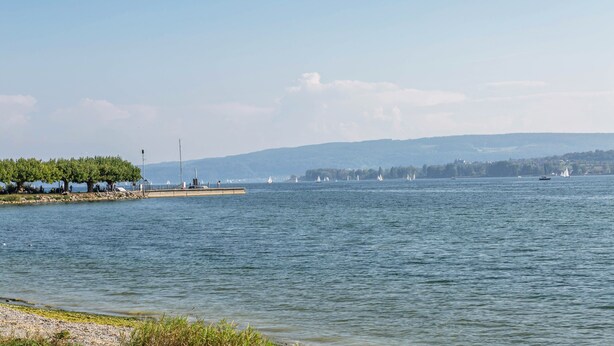 A calm lake with boats, a dock, and distant hills.