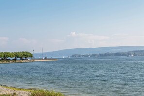 Un lac paisible, avec des bateaux, un quai et des collines qui se dessinent à l’horizon.