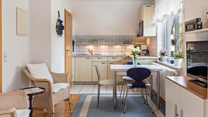 A modern kitchen with a dining area, wooden cabinets, and a TV.