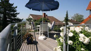 A deck with a table and chairs, an umbrella, and white flowers.