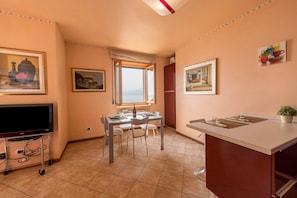 A kitchen with a dining table, chairs, a TV on a cart, and a window with a view.