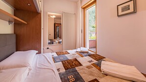 Een slaapkamer met een bed, een raam met gordijnen, een lijst met foto aan de muur en een houten hoofdeinde.