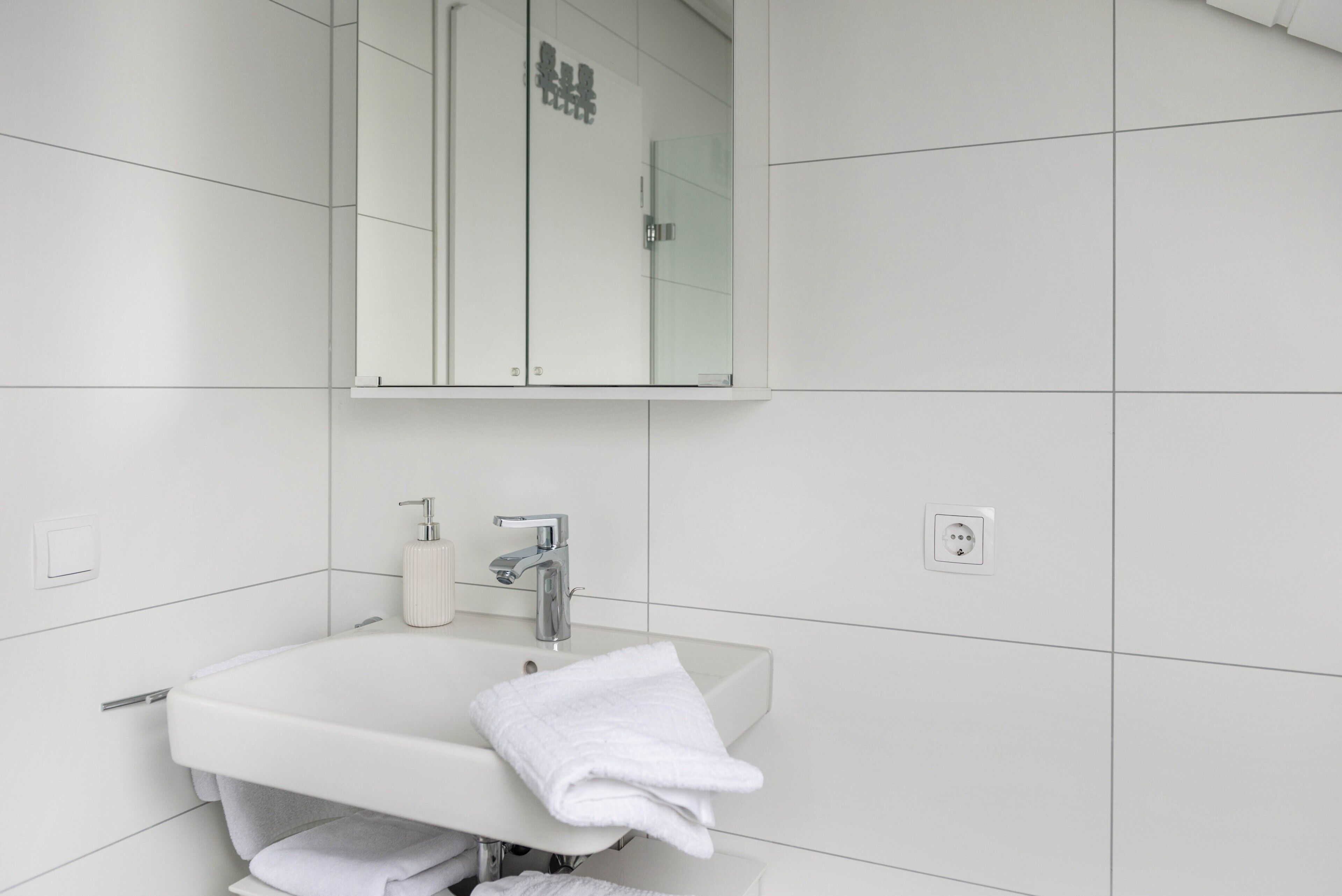 Ein Badezimmer mit einem weißen Waschbecken, einem Spiegel darüber und einem Handtuch auf dem Waschbecken.