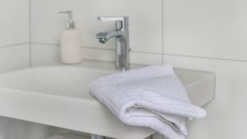 Un baño con lavamanos blanco, grifo y toalla.