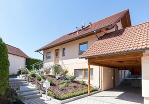 Et toetagers hus med tegltag, en overdækket veranda og en anlagt have.