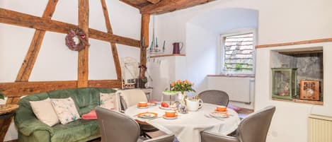 A cozy dining area with a wooden ceiling, a green sofa, and a table set for two.