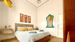 Une chambre à coucher avec un grand lit, une tête de lit en bois, une table de chevet avec une lampe et un miroir fixé au mur.