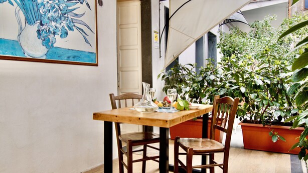Un coin repas avec une table en bois, deux chaises, un vase de fleurs et une plante en pot.