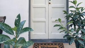 Une porte double blanche, avec un paillasson sur lequel est écrit « Bienvenue ».