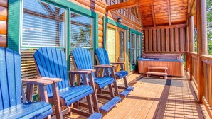 A wooden cabin with a porch, blue Adirondack chairs, a hot tub, and a wooden deck. - A Higher Calling, Spacious Smoky Mountain Getaway –Perfect for Families & Groups (Pigeon Forge)