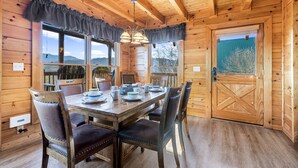 A wooden cabin with a dining table set for four, surrounded by chairs. - A Higher Calling, Spacious Smoky Mountain Getaway –Perfect for Families & Groups (Pigeon Forge)