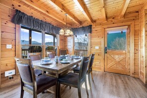 A wooden cabin with a dining table set for four, surrounded by chairs.