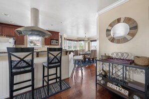 Una cocina con armarios de madera, una isla central con taburetes de bar, una lámpara colgante y un espejo decorativo en la pared.
