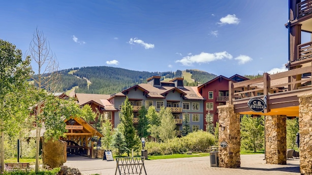 Eine Lodge mit mehreren Gebäuden, einem Steineingang und einem Berg im Hintergrund.