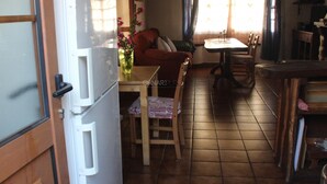 Une cuisine équipée d’un réfrigérateur, d’une table à manger, de chaises et d’une fenêtre avec des rideaux.