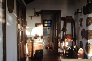 A narrow hallway with rustic decor, including a barrel, pottery, and wooden furniture.