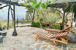 A stone patio with wooden lounge chairs and a swing set. - Traditional Canarian Retreat: Casa Francisco with Private Pool, Terrac (Puntagorda)