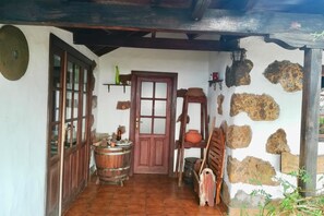 A rustic room with a wooden door, a window, a barrel, and stone walls.