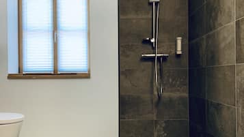 Un baño moderno con ducha, inodoro y ventana.