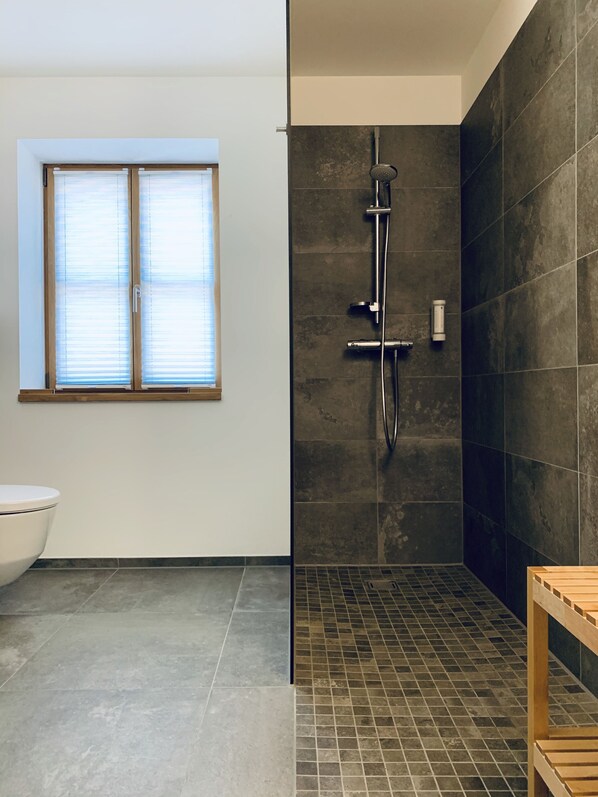 A modern bathroom with a shower, a toilet, and a window. - Stadthotel Kachelofen (Krumbach)