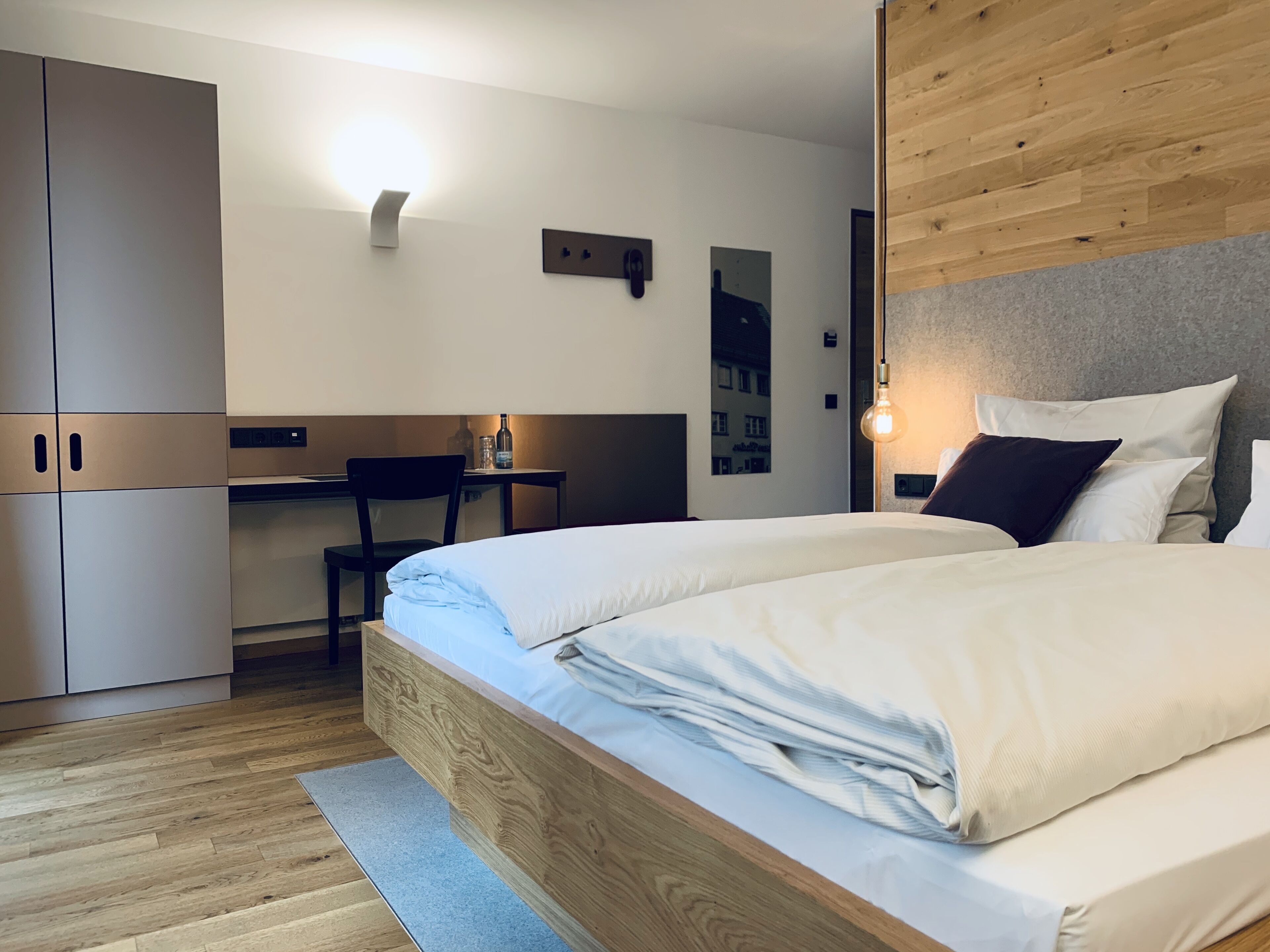 Una habitación de hotel moderna con una cama de madera, un escritorio y un armario.