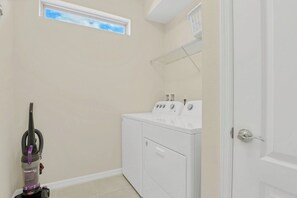 A laundry room with a washing machine, dryer, and a vacuum cleaner. - Private Pool & Spa • Spacious TV Loft • Gated Resort Waterslides • Near Disney (Davenport)