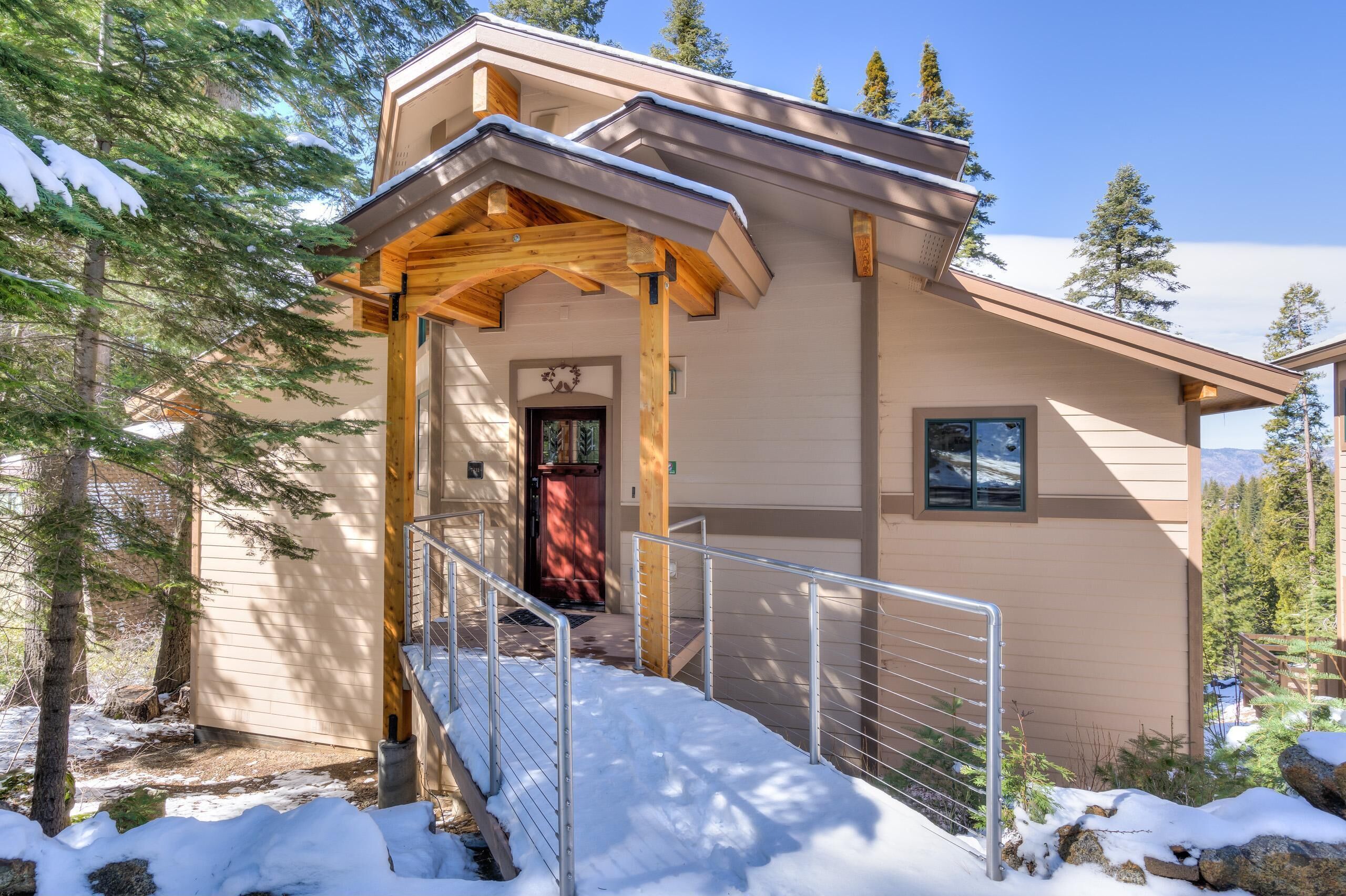 A modern building with a wooden porch, a red door, and a metal railing.