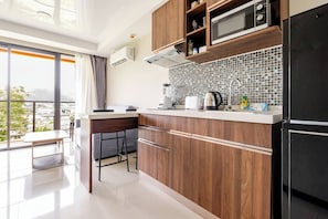 A modern kitchen with wooden cabinets, a microwave, a kettle, and a coffee maker.