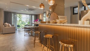 A modern kitchen with a bar area, bar stools, and a dining set.
