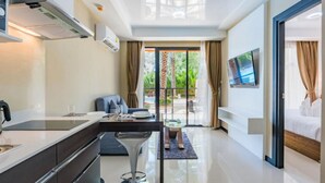 A modern hotel room with a kitchen area, a dining table, and a large bed. - Mai Khao Beach Condotel by Villacarte (Mai Khao)
