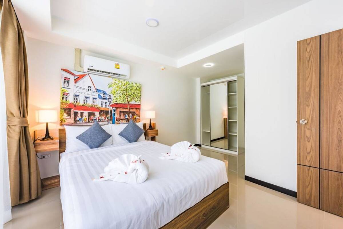 Ein Hotelzimmer mit einem großen Bett, einem Schrank, einem Spiegel und einem Bild an der Wand.