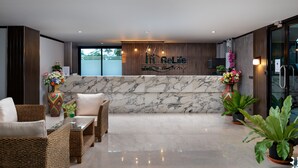 A reception area with a marble reception desk, wicker furniture, and potted plants.