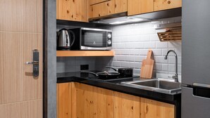 A modern kitchen with wooden cabinets, a stainless steel sink, a microwave, and a kettle.