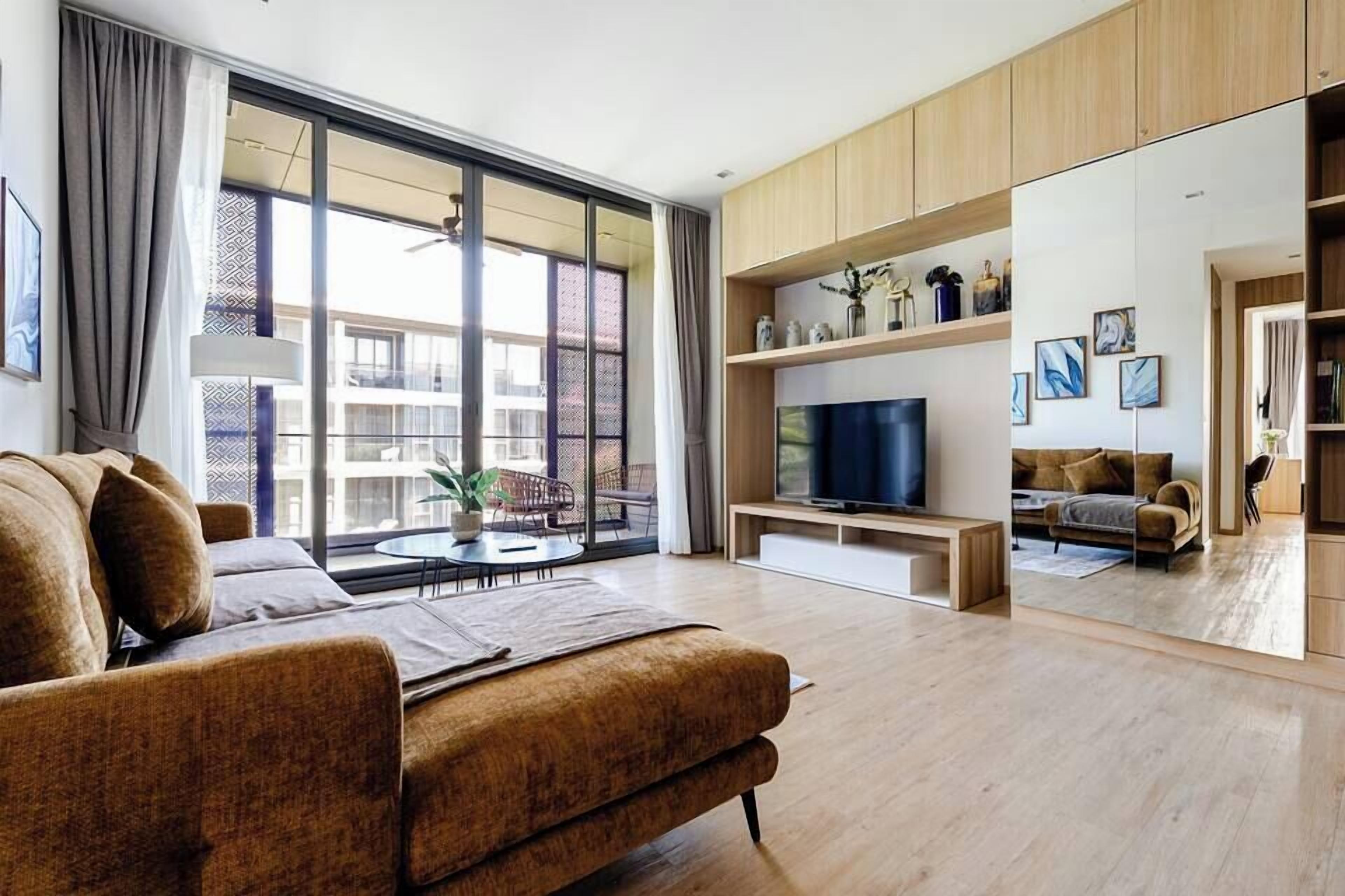A modern living room with a sofa, TV, and large windows.