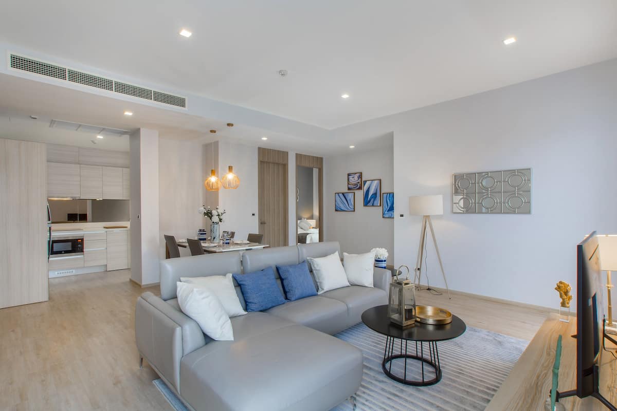 A modern living room with a grey sectional sofa, a coffee table, and a flat-screen TV.