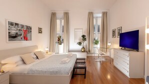 A modern hotel room with a bed, bedside tables, a TV, a desk, and a large window. - Babuino Apartments - Piazza di Spagna (Rome)