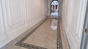 A long, narrow hallway with white walls and a marble floor. - Babuino Apartments - Piazza di Spagna (Rome)