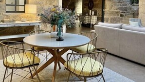 A dining area with a round table and four chairs, a stone wall, and a staircase leading to an upper level. - EXCLUSIVE RURAL HOUSE WITH POOL IN LAS RIAS BAIXAS  (MEIS)