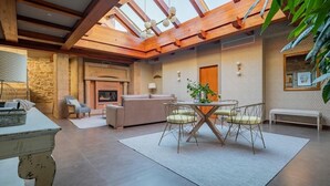 A spacious living area with a fireplace, a dining table with chairs, and a large window with a wooden ceiling. - EXCLUSIVE RURAL HOUSE WITH POOL IN LAS RIAS BAIXAS  (MEIS)