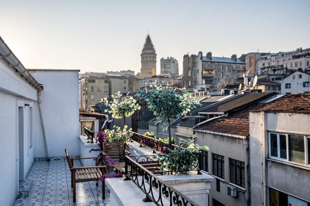 A rooftop terrace with a view of a historic tower, surrounded by residential buildings.