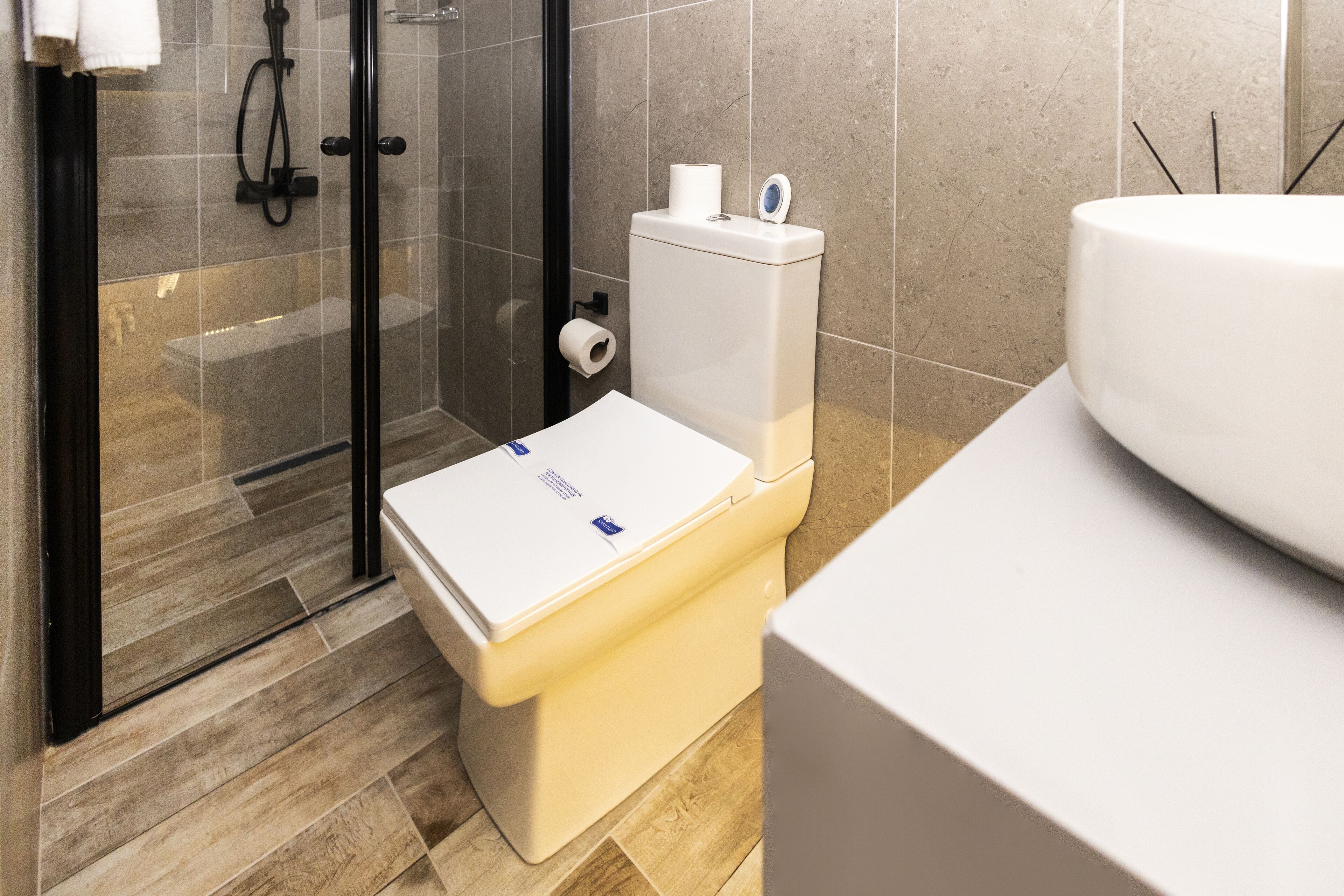 Un baño moderno con inodoro, cabina de ducha de vidrio y lavamanos.