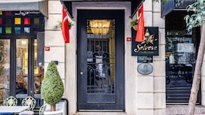 A hotel entrance with a black door, a sign reading "Hotel Galata 1875", and a "Selves Collection" sign. - Selvese Suites – Serviced Living in Galata (Istanbul)