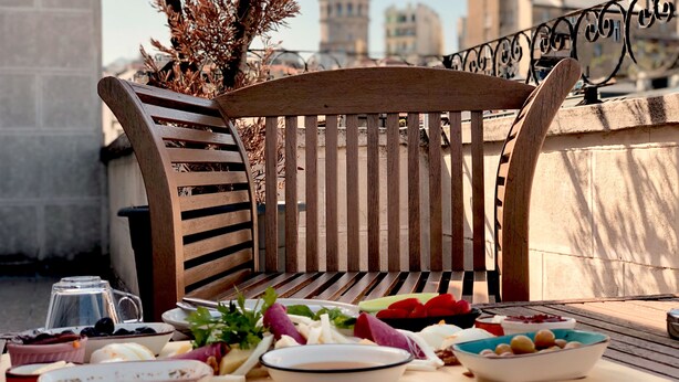 A wooden bench with a table in front of it, containing various dishes and a coffee pot. - Selvese Suites – Serviced Living in Galata (Istanbul)