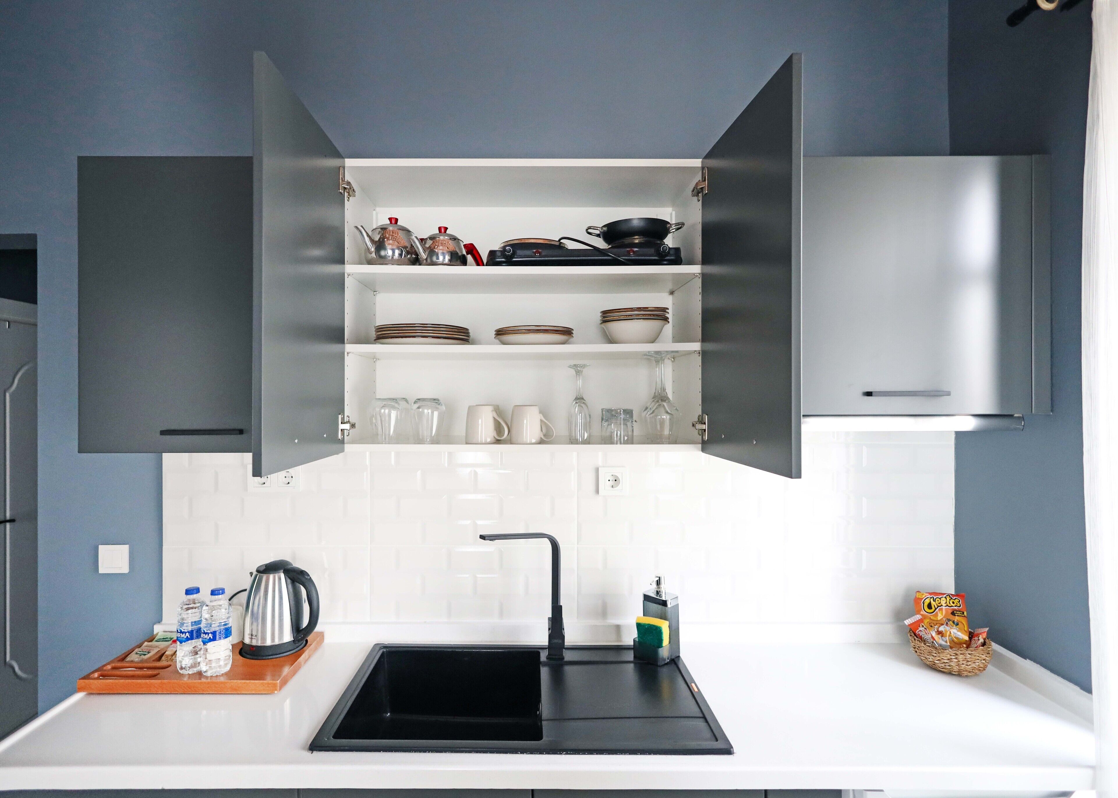 A modern kitchen with a black sink, white countertops, and a built-in cabinet above the sink.