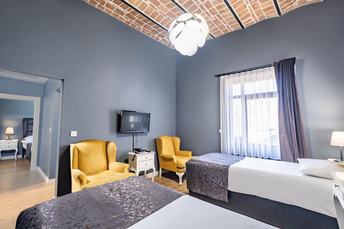 A hotel room with two beds, a TV, and a brick-patterned ceiling.
